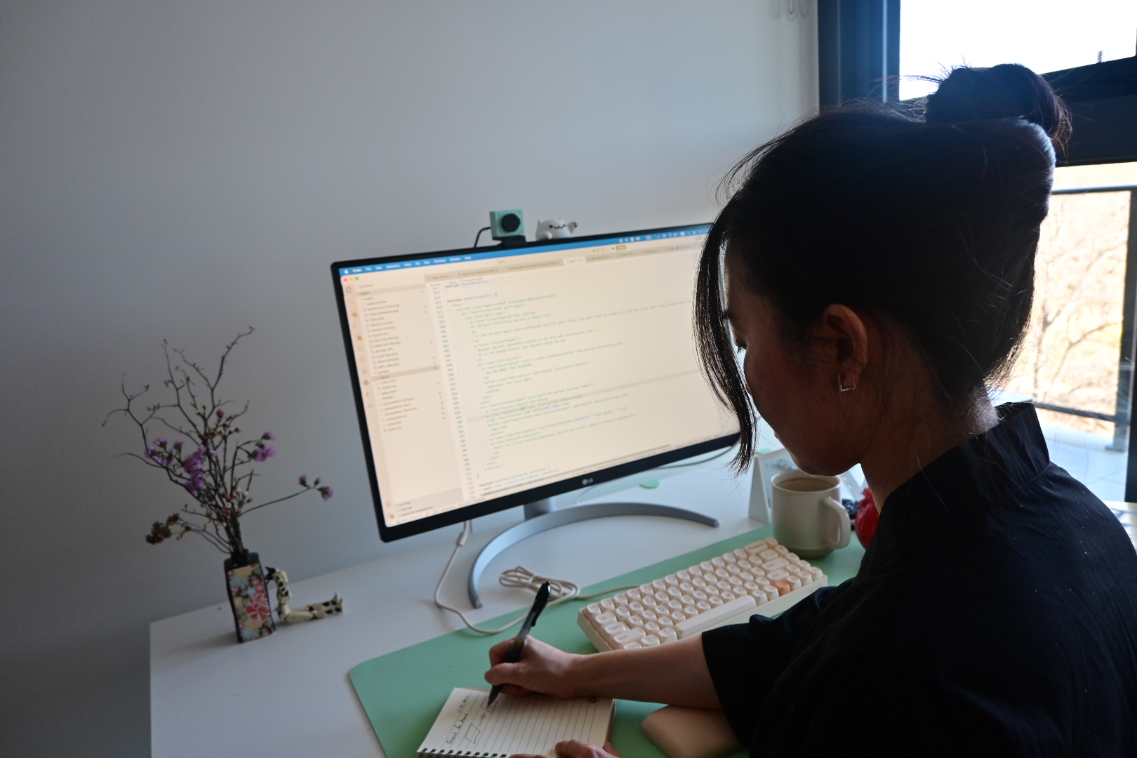 Ira developing a quest at her desk, working between code and handwritten notes